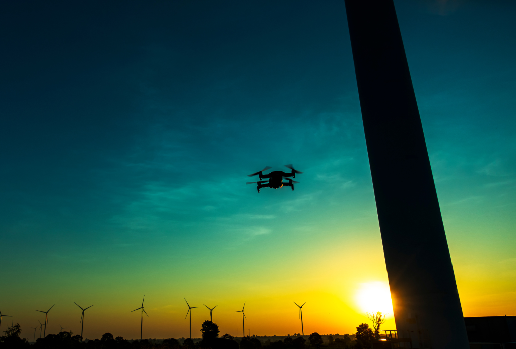 Drone flying at sunset with wind turbines