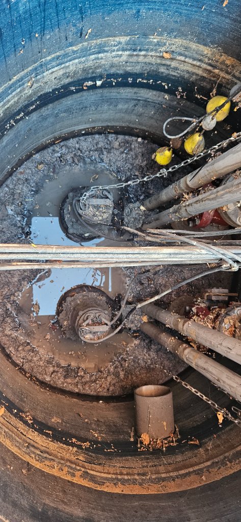 Interior view of a wet well showing piping, guide hardware, and installed equipment.