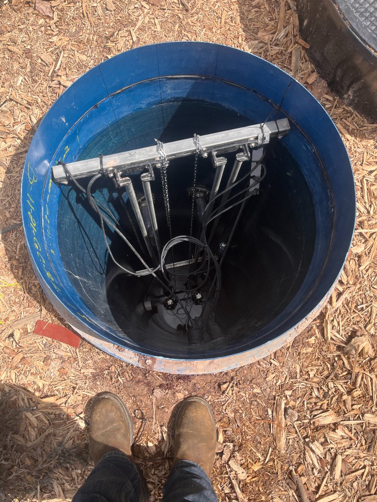 Wet well interior with discharge piping and pump guide hardware