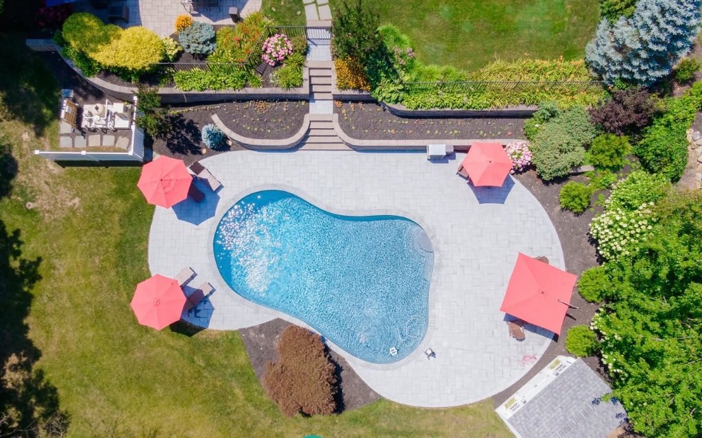 Aerial freeform pool with red umbrellas