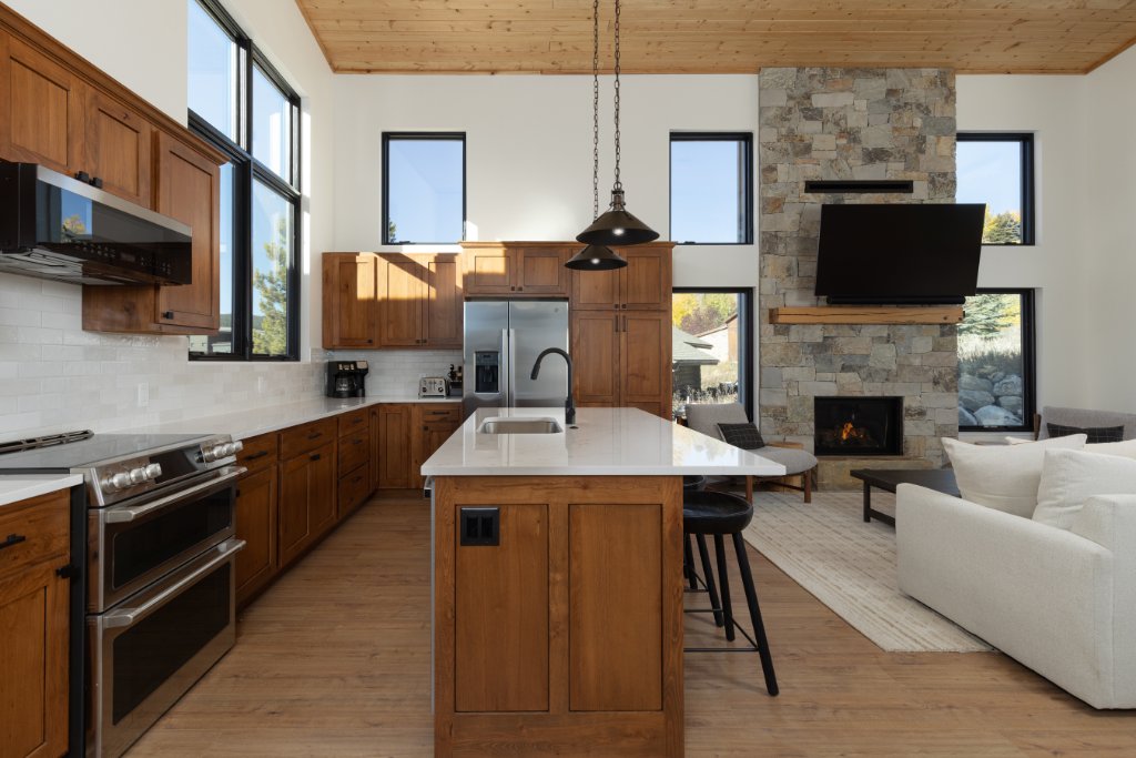 Kitchen — island with quartz counters, stone fireplace & living room views