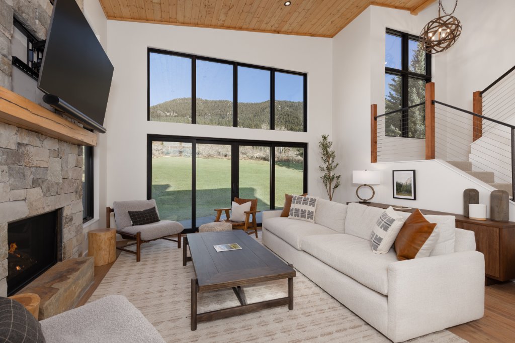 Living room — stone fireplace, floor-to-ceiling windows & mountain views