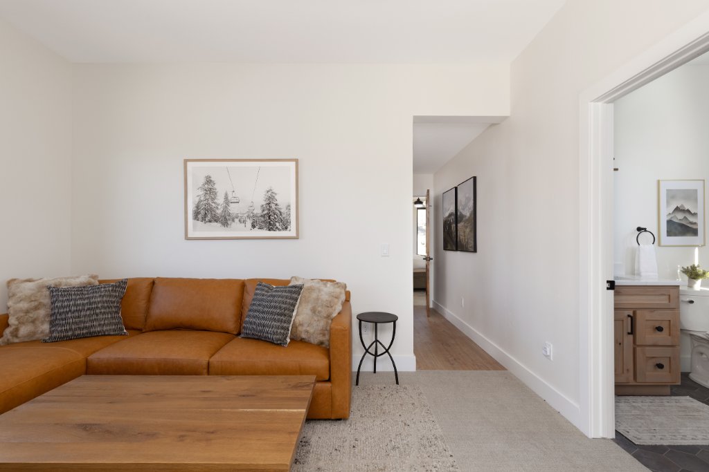 Den — leather sofa with ski art & hallway to bathroom