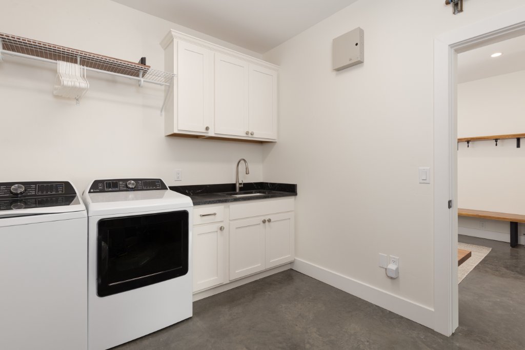 Laundry room — washer, dryer, utility sink & white cabinets