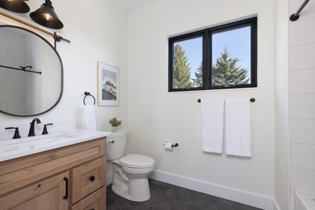 Bathroom 3 — round mirror, wood vanity & mountain view window