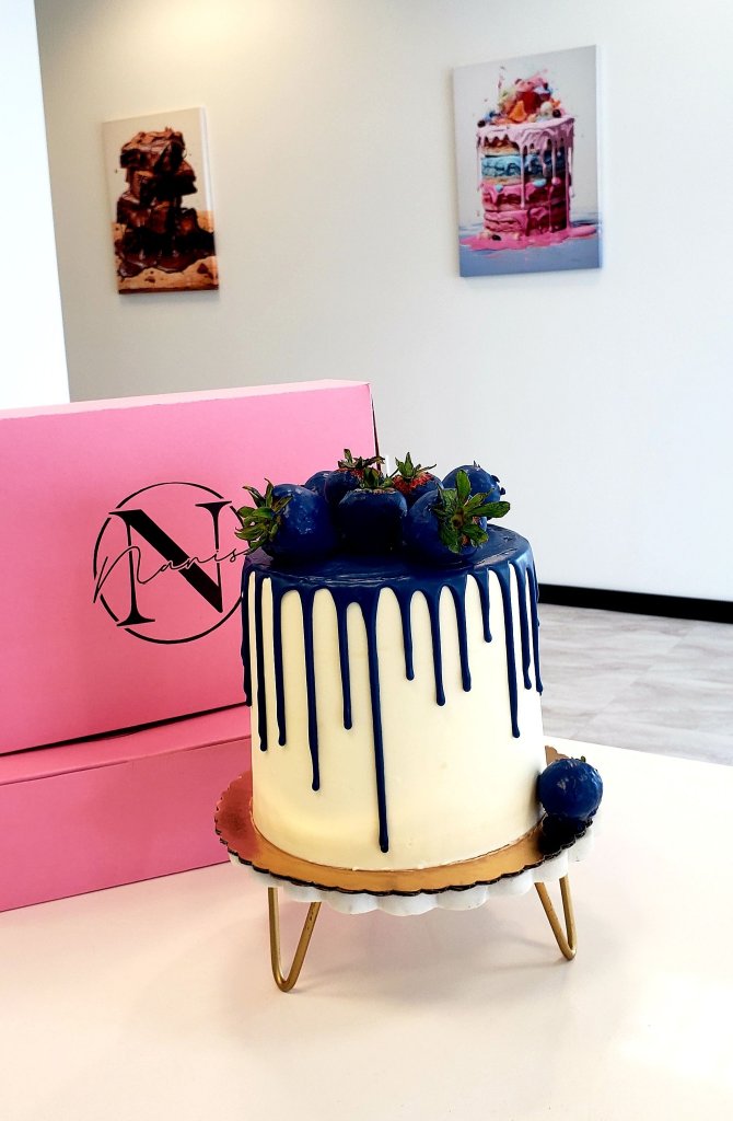 White cake with navy blue drip and chocolate-dipped strawberries