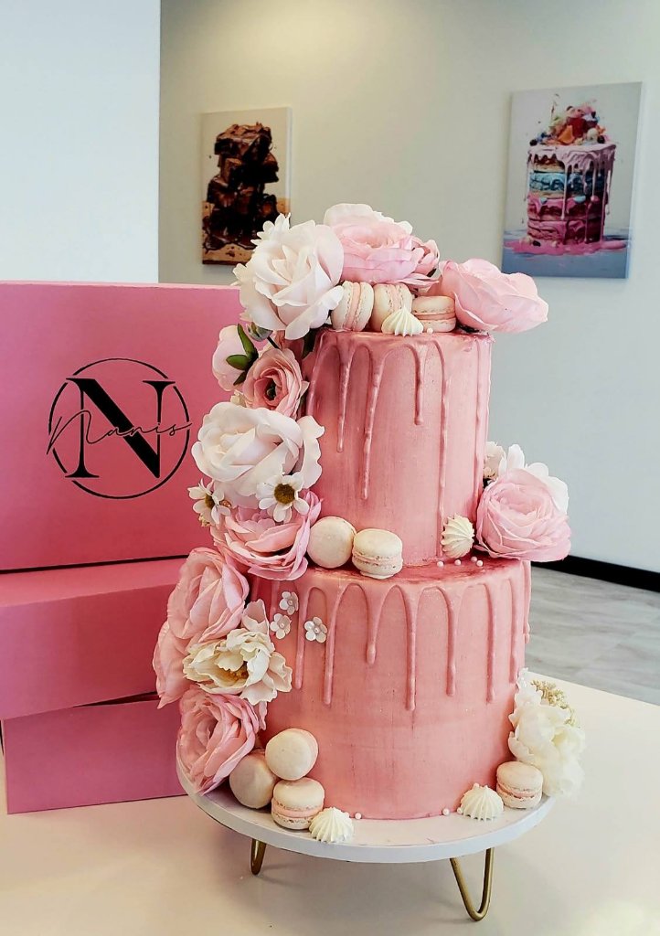 Three-tiered pink floral drip cake with macarons