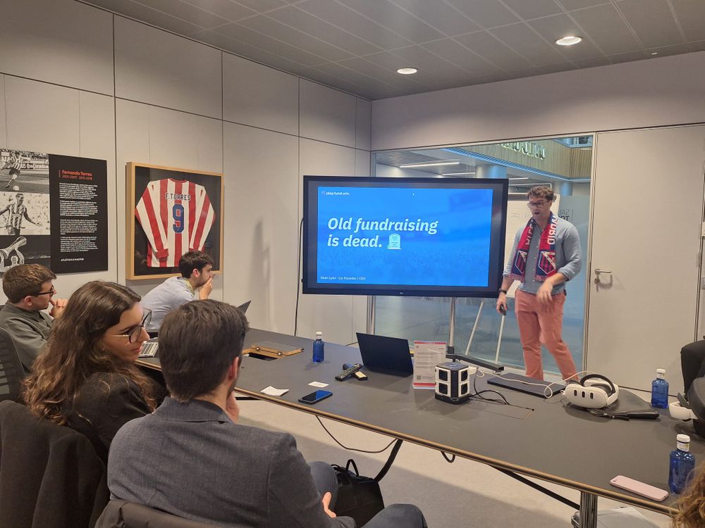 A small audience watching a presentation on a wall screen in a club meeting room