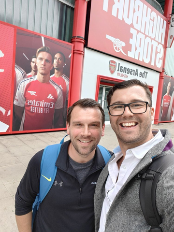 Two people outside the Arsenal store, a player mural on the wall behind