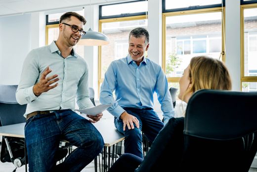 A Trusted Media photograph: three colleagues talking in a bright modern office
