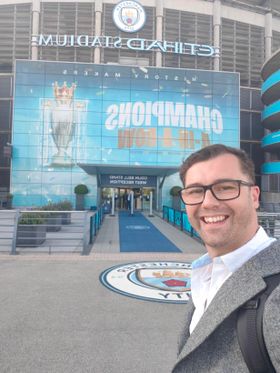 Standing outside the Etihad in front of a Manchester City champions banner