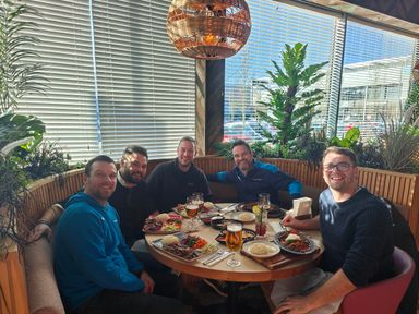The Play Fund Win team round an outdoor table on a roof terrace, plates everywhere