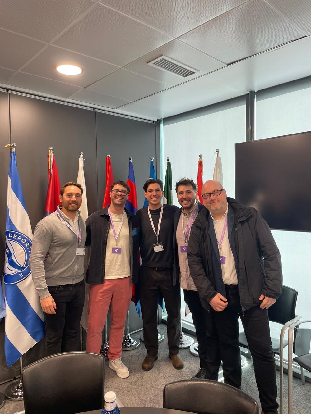 A group standing together in a meeting room lined with national flags
