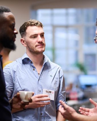 Portrait of Dean Lynn, a networking expert and founder, engaged in conversation at a professional event.